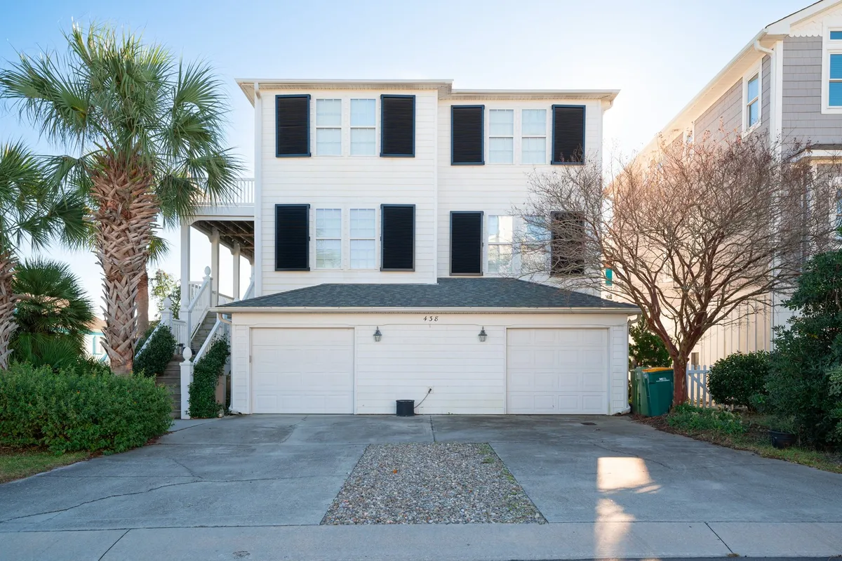 A welcoming exterior view of the property with palm trees, a spacious front porch, double garage doors, and large windows with shutters, hinting at private community living.