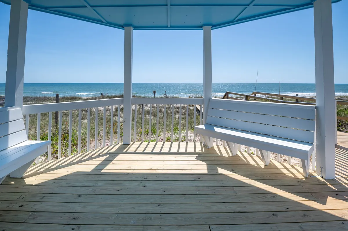 An elevated view over the ocean from a wooden deck with white benches. The tranquil vantage point is ideal for groups to relax, watch sunrises, spot marine life, or enjoy a seaside picnic. The setting exudes togetherness and calm—perfect for winding down after a day of adventure.