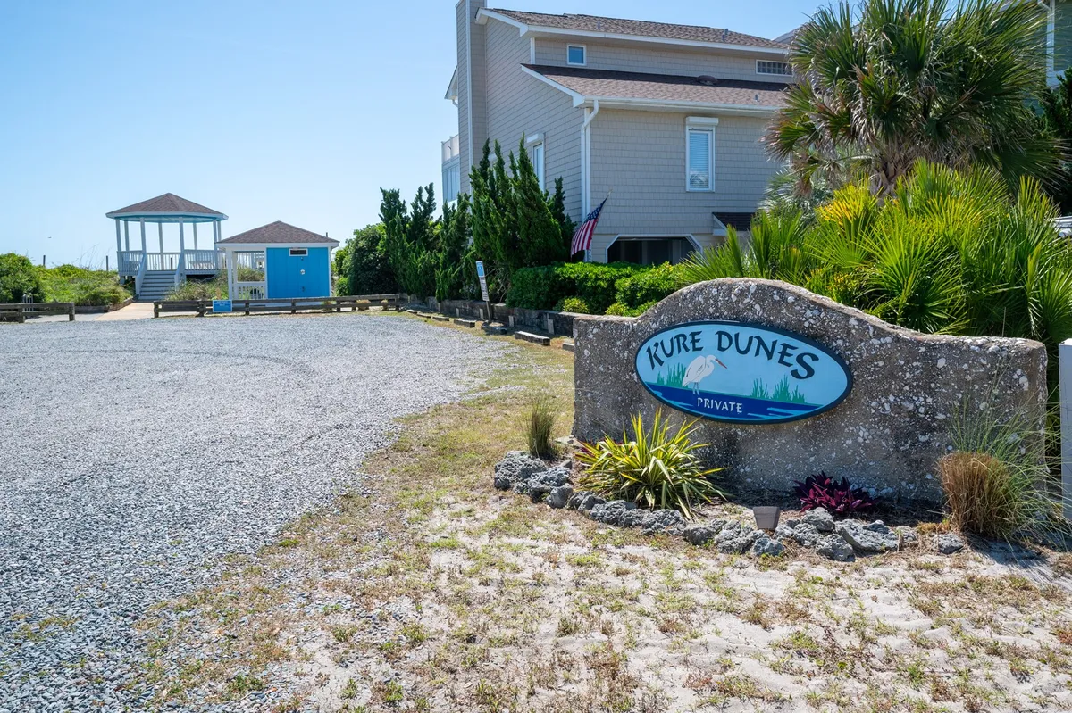 The exterior of Bon Temps is framed with lush landscaping, a welcoming property sign, generous parking, and a charming gazebo. The sunset view adds a warm, communal feeling—a place where families can gather outdoors to relax, host group activities, or enjoy the ocean breeze.