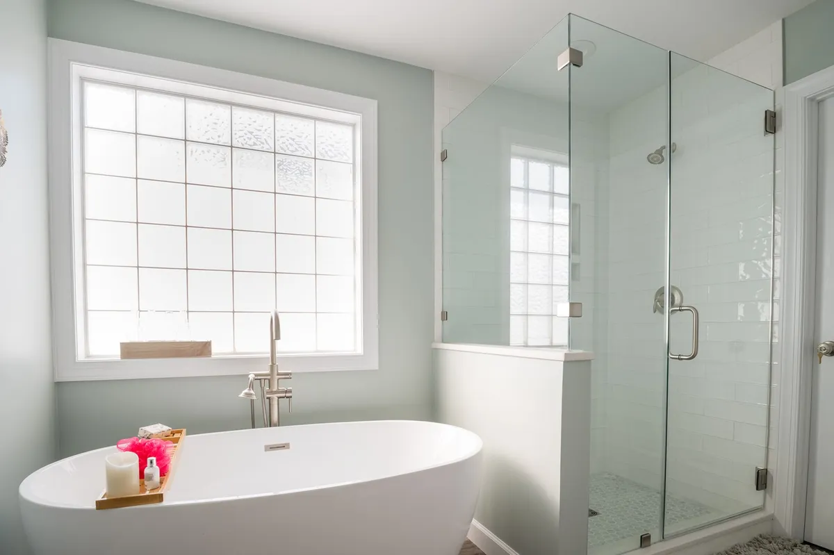 A spa-inspired bathroom with a freestanding bathtub, a glass shower enclosure, and a large window letting in soft light. The tranquil setting is perfect for unwinding with a soak or refreshing after a long day.