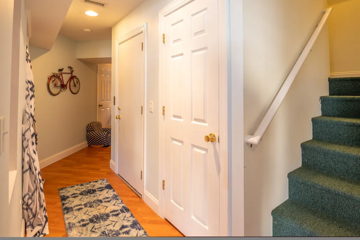 An inviting entryway featuring a decorative bike on the wall, a cozy rug, and stairs leading upward. The space radiates warmth and the sense of arrival, underscoring the welcoming, family-friendly environment of the property.